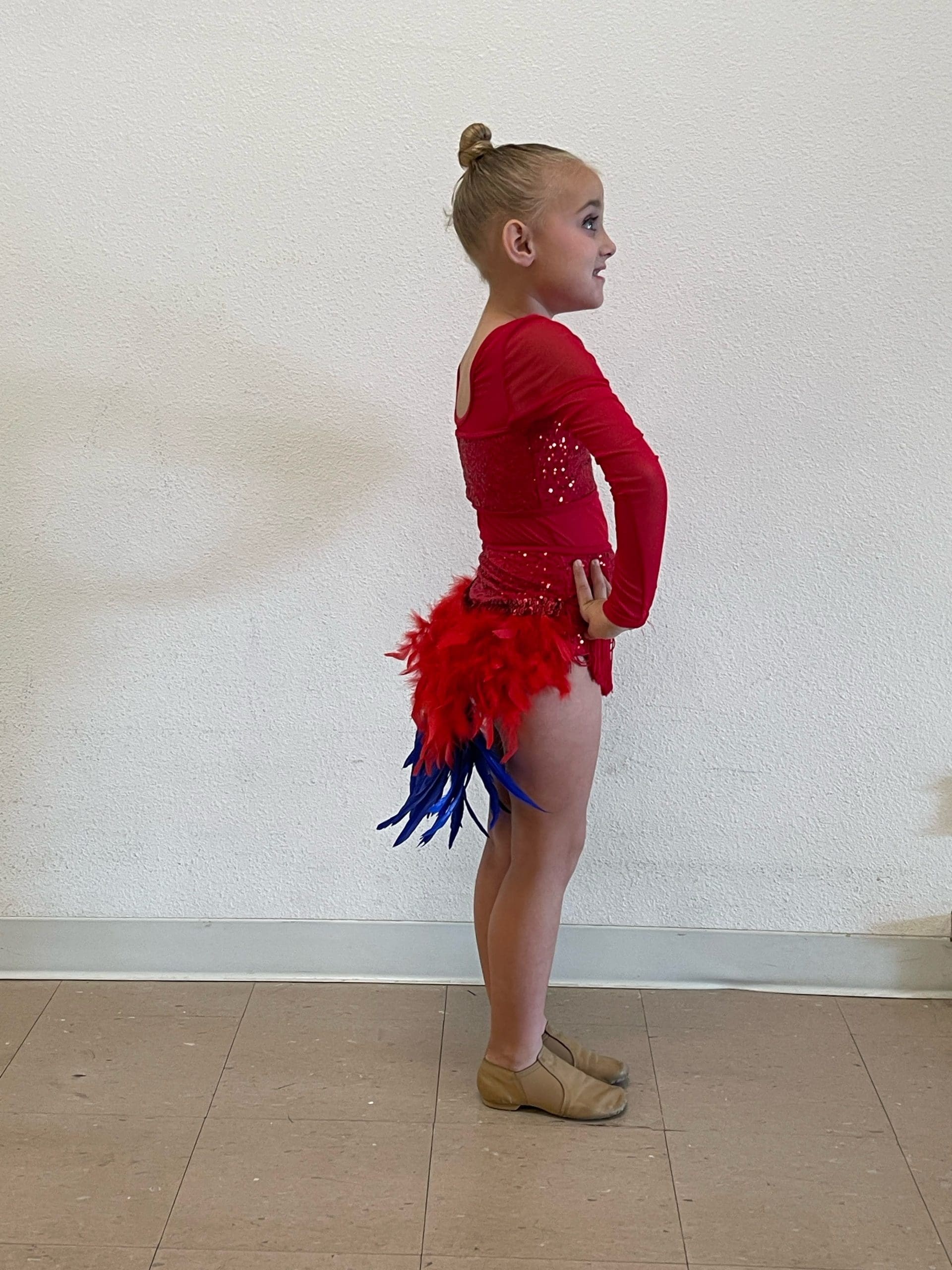 young dancer in red costume with feather embellishmentsDance costume sketch, rhinestones, and performance fabric details
