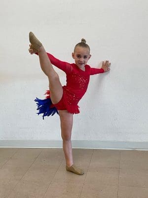 SOLO DANCER IN A COSTUME EMBELLISHMENTS DONE BY SEWN 2 DANCE IN RED COSTUME WITH FEATHERS IN BLUE AND RED