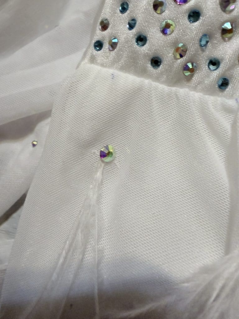 girl in a custom competitive costume lyrical pink and green alterations white rhinestones and feather embellishment