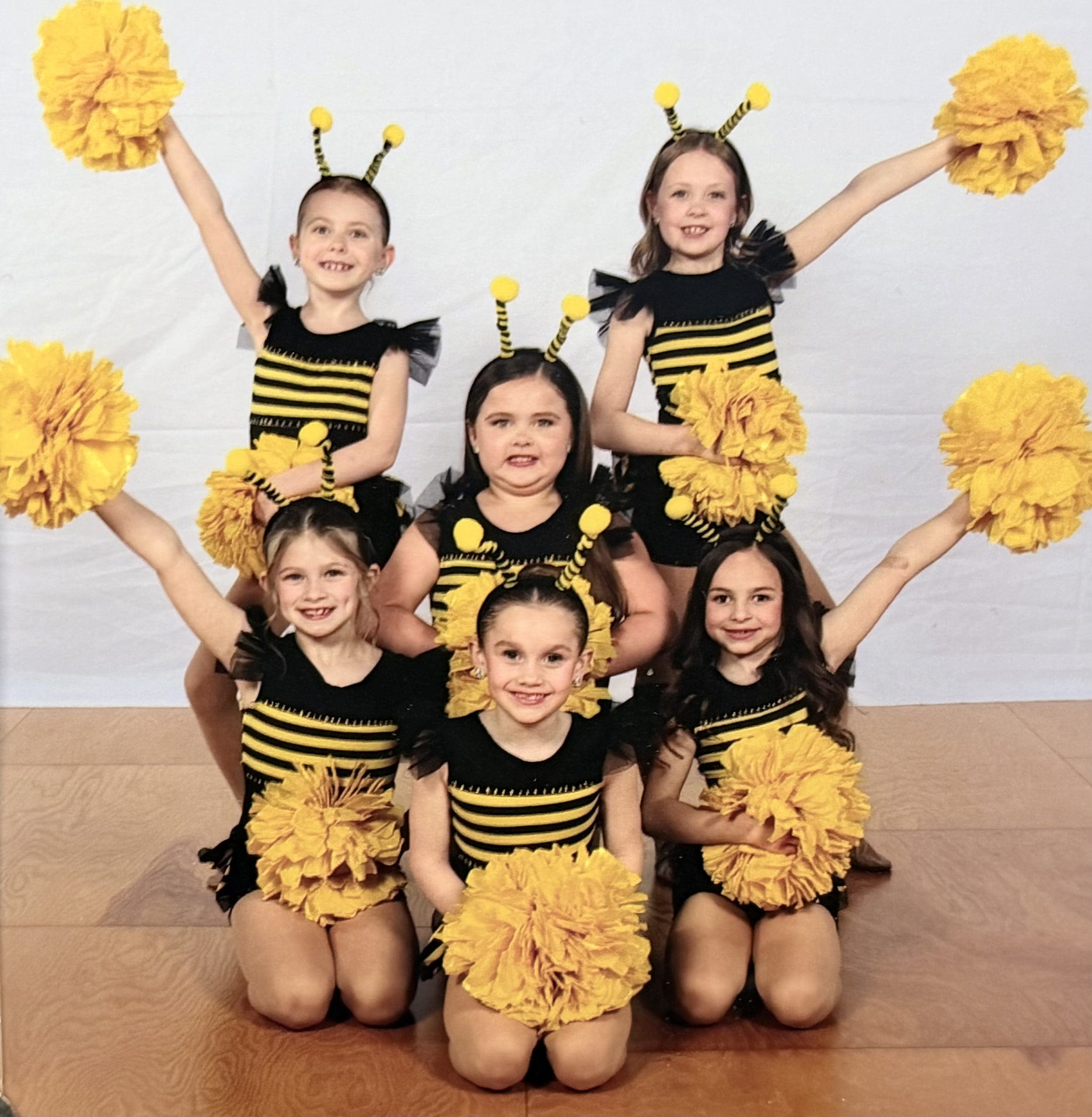 custom pom costumes for a 5678! Dance Studio 2025-26 tiny team out of McCook Lake, SD in their one-of-a-kind bee pom costumes black and yellow with tulle sleeves and skirts embellishments rhinestones costumes design and created by sewn 2 dance