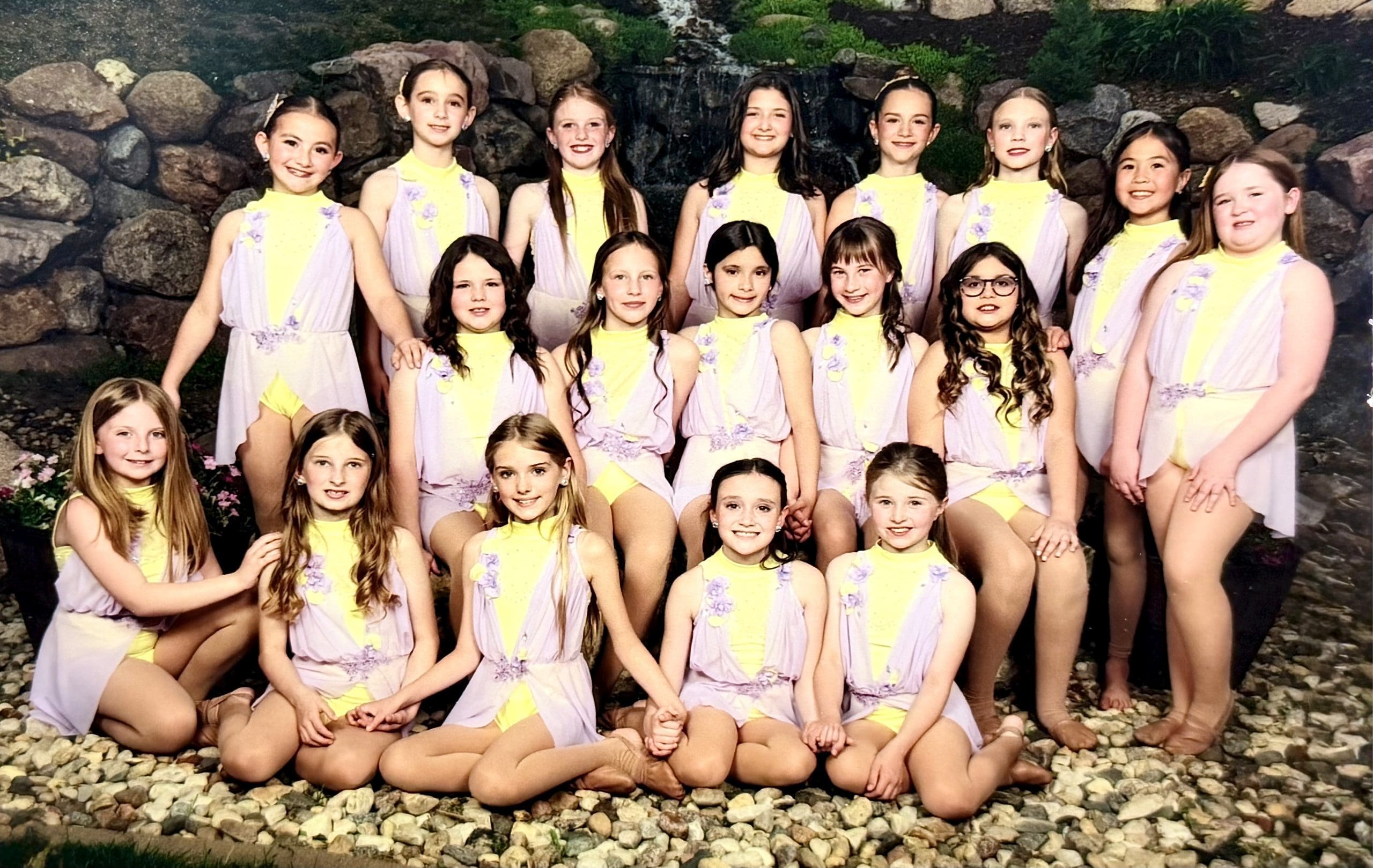 Mini dance team in pale-yellow lyrical costumes with purple lace, skirts and handmade flowers.