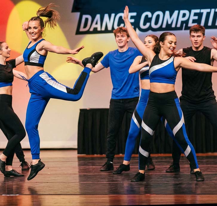 team dancing at a dance competition on stage in blue, white and black costumes